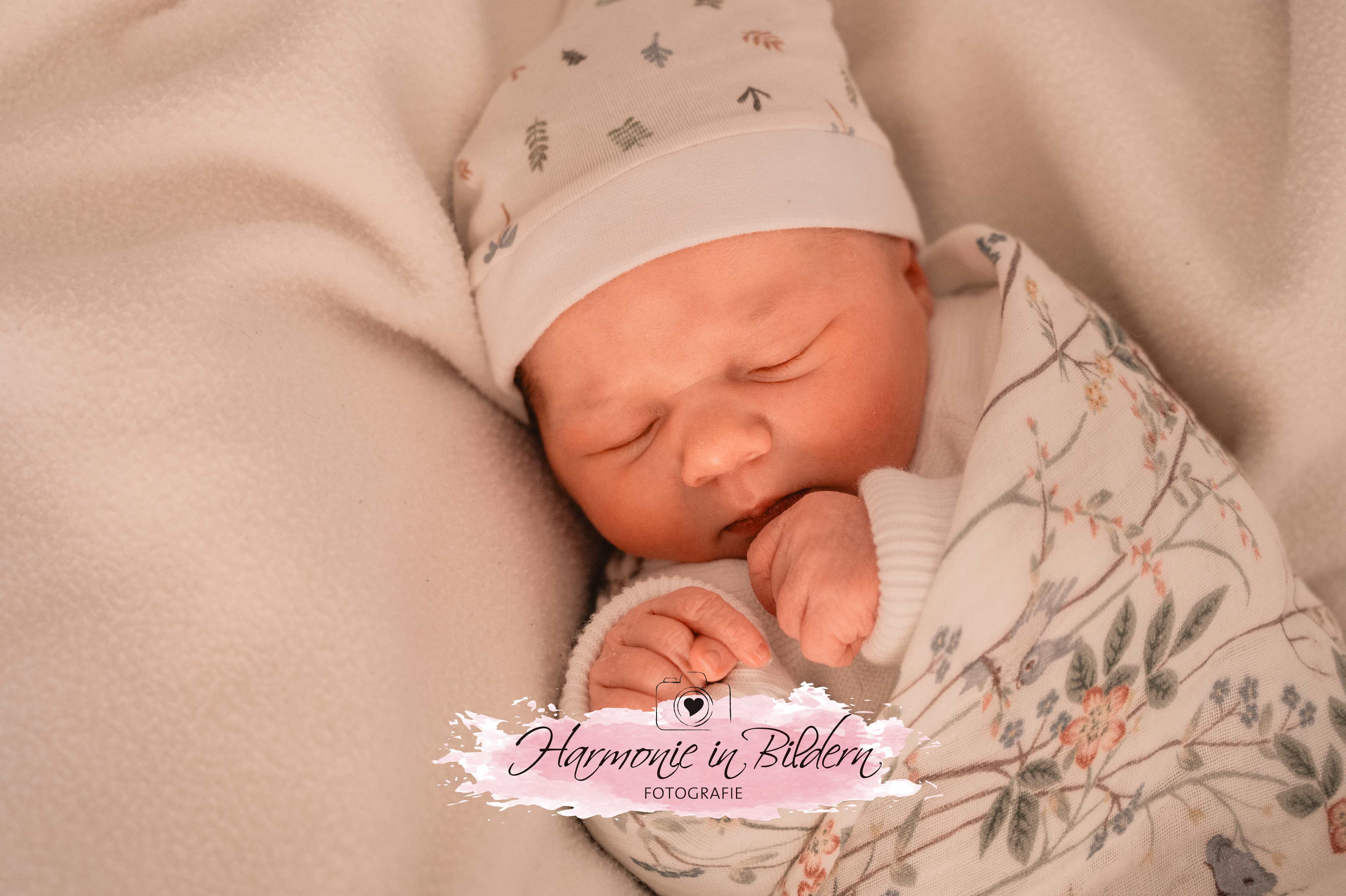 Neugeborenes Mädchen auf weisser decke mit Mütze