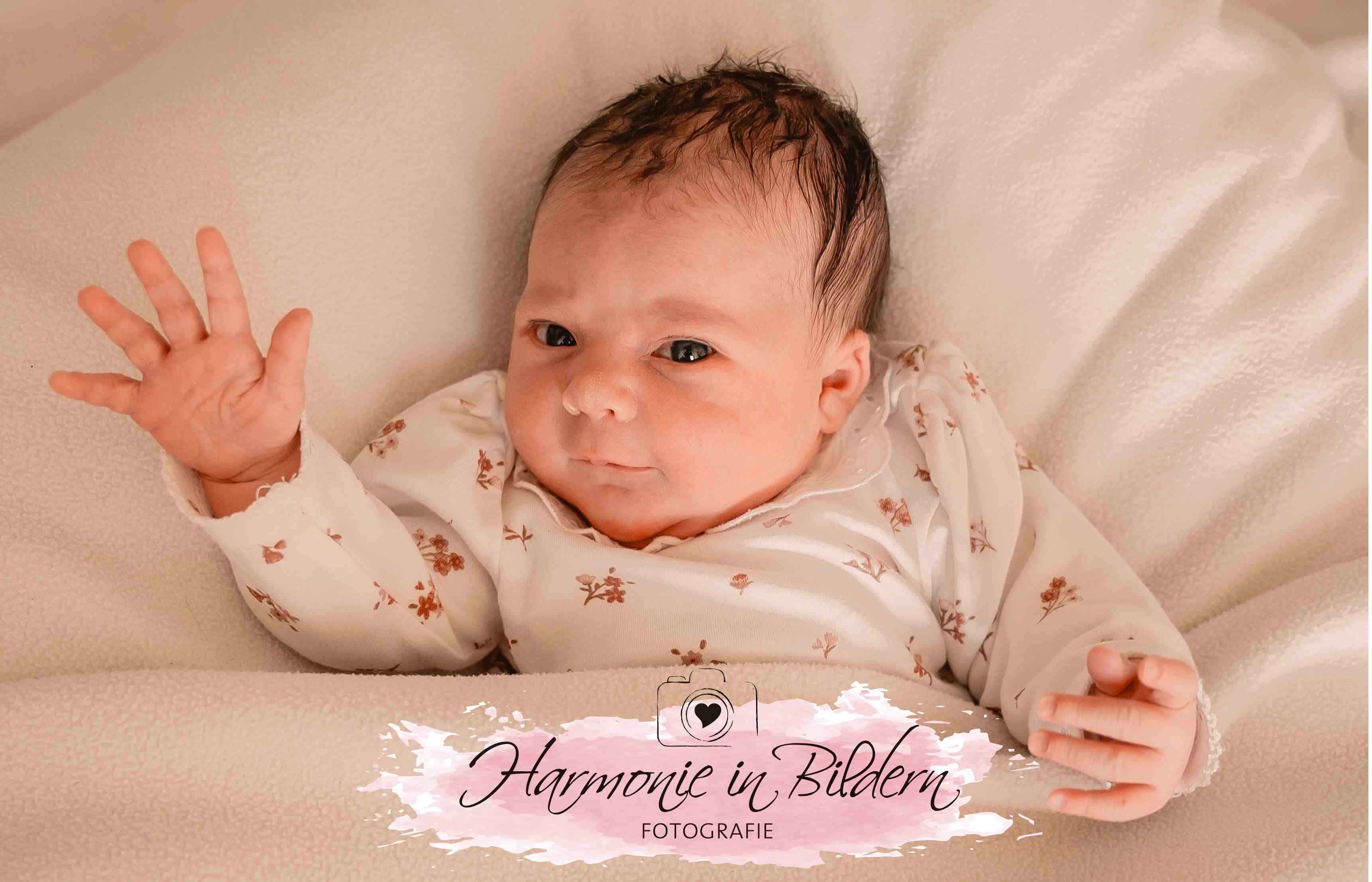 Neugeborenes Mädchen dunkle Haare hebt die Hand