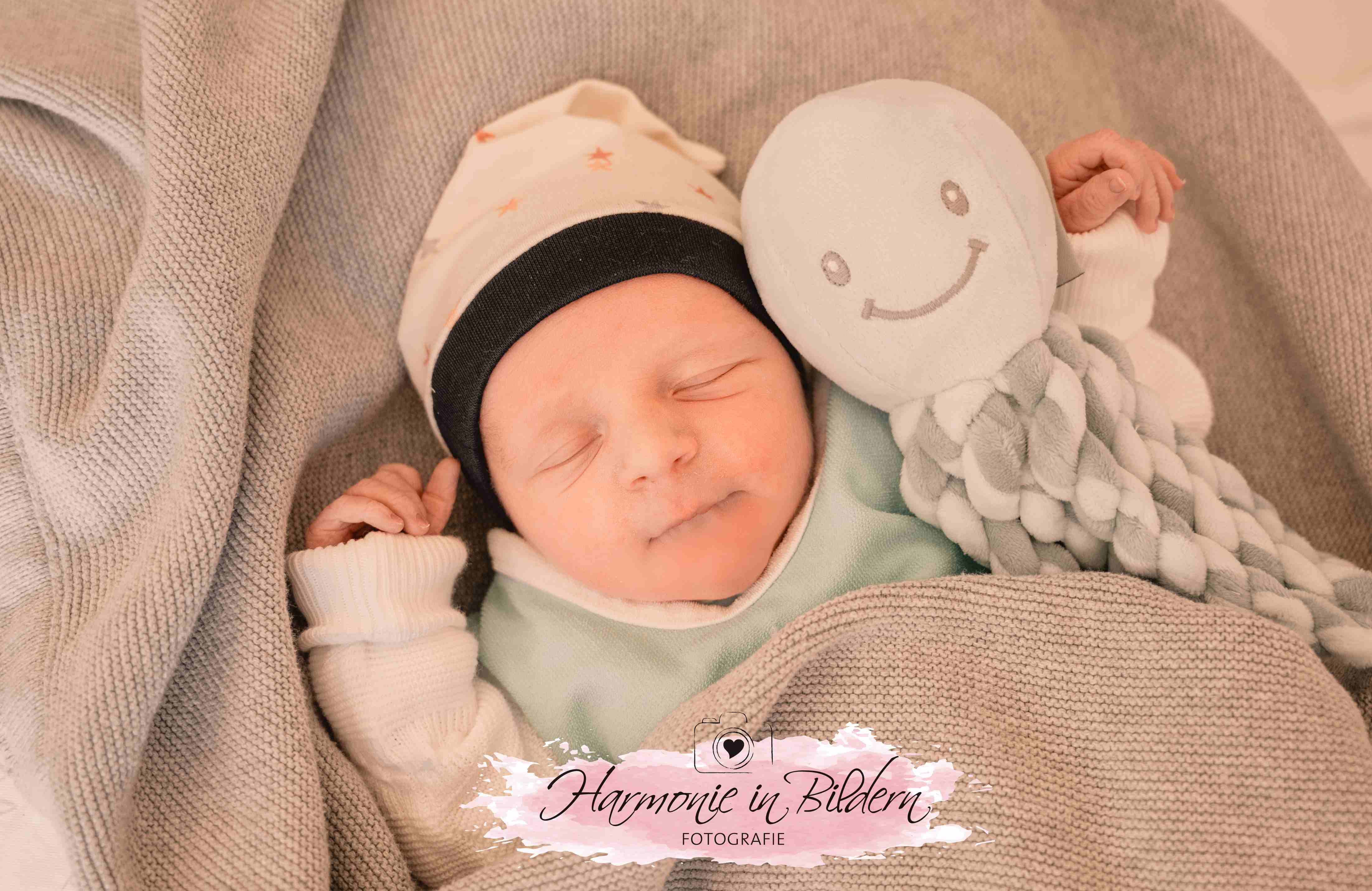 Neugeborener Junge auf blauer Decke mit Kuscheltier
