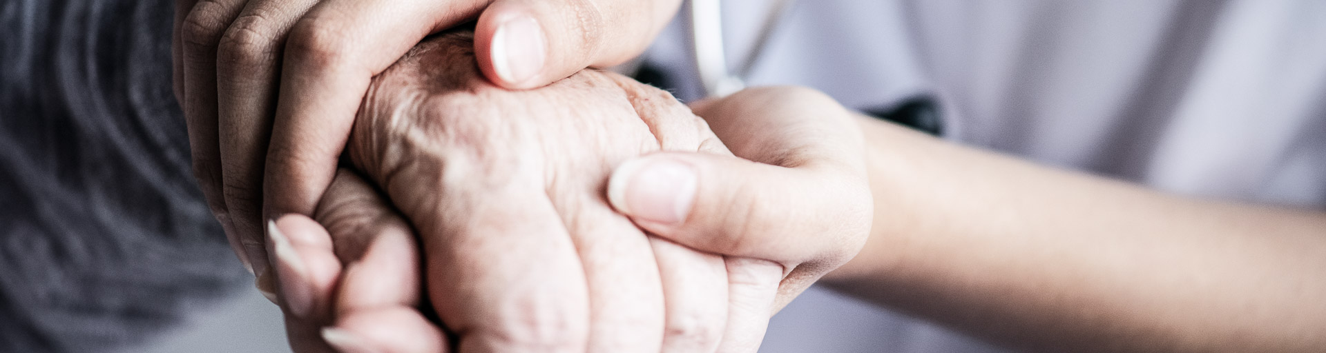 Krankenschwester hält die Hand eines älteren Patienten